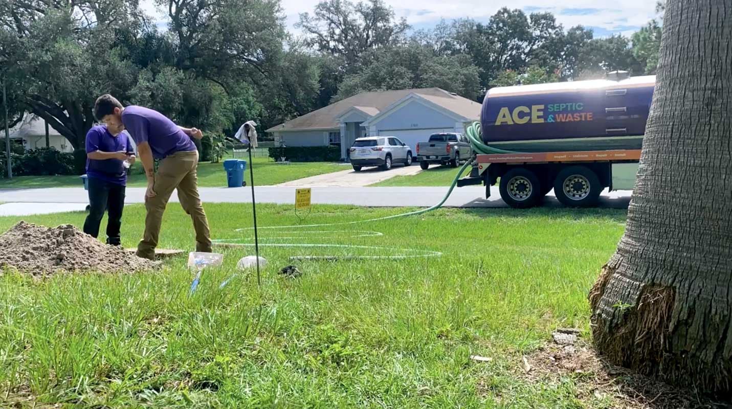 Two people looking into a hole and inspecting a septic system.