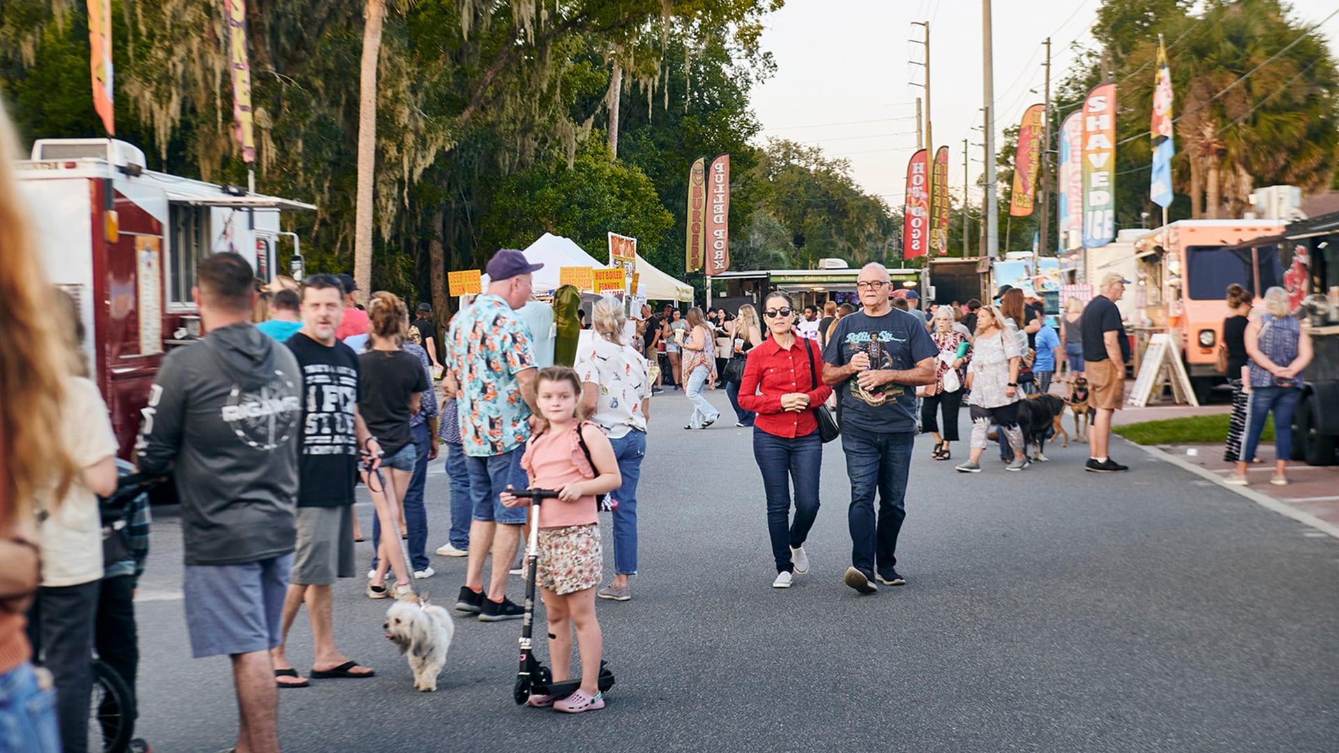 Attendees enjoying the lively atmosphere at the Boomtown Days Festival in Dunnellon, FL, with food trucks, vendors, and families gathered under the canopy of oak trees.